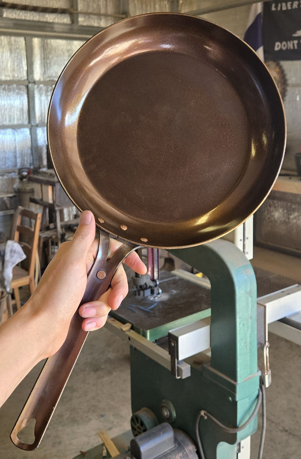 Hand holding a Texas Pan Company carbon steel skillet in the shop in Gilmer, Texas