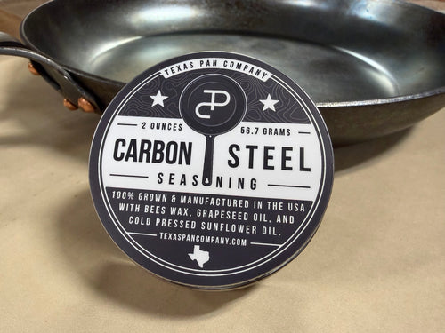 Carbon Steel Seasoning tin, closed, leaning against a carbon steel skillet
