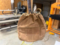 Canvas Skillet Bag in tan waxed canvas with The Original's handle coming out the drawstring top, hanging in the Texas Pan Company shop