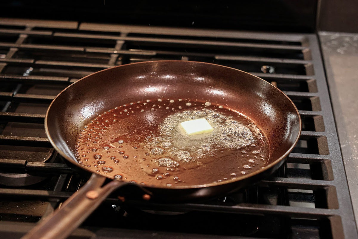 A pat of butter melting in The Original carbon steel skillet on a gas burner