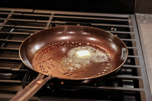 A pat of butter melting in The Original carbon steel skillet on a gas burner