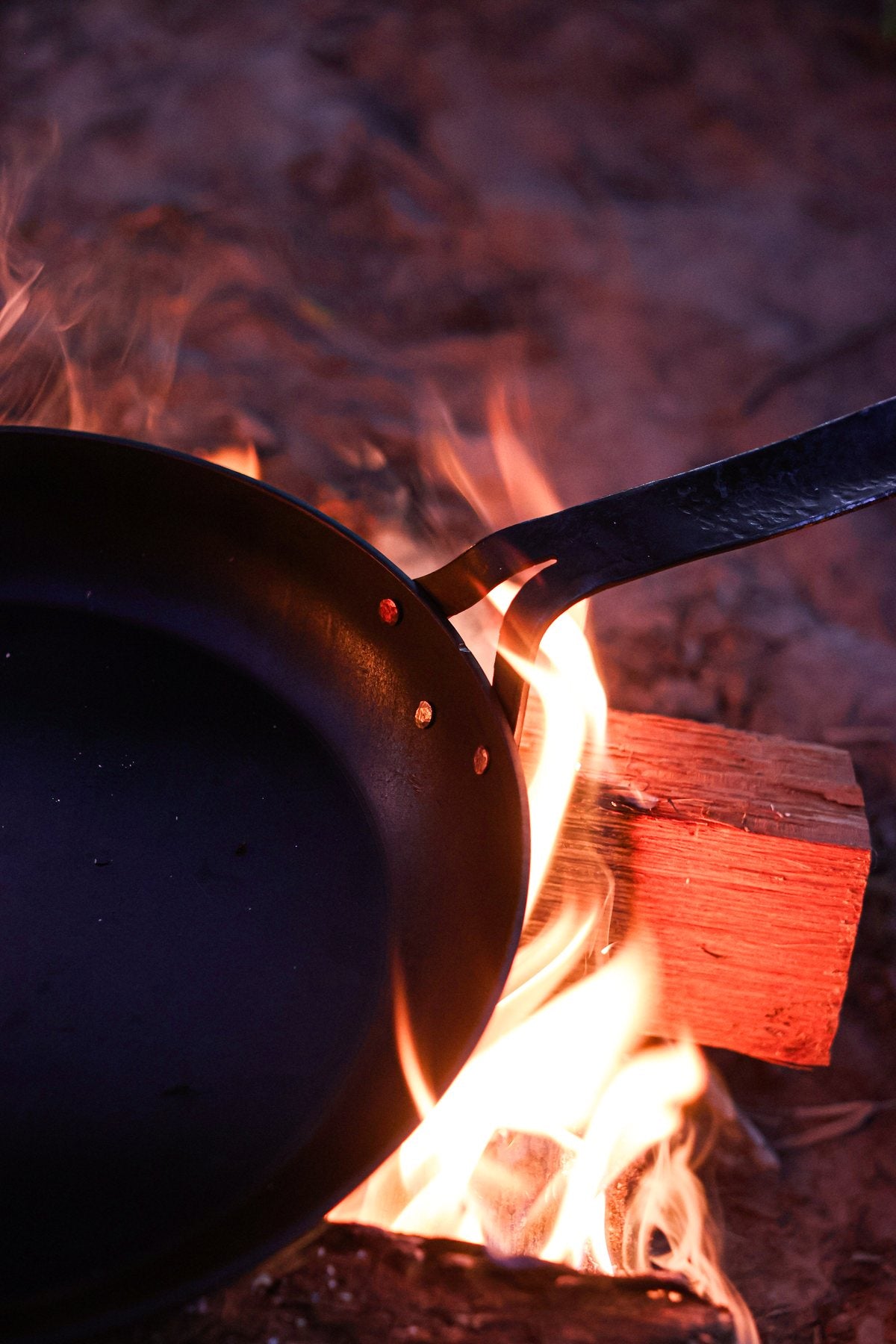 Copper rivets joining a carbon steel skillet and handle over fire