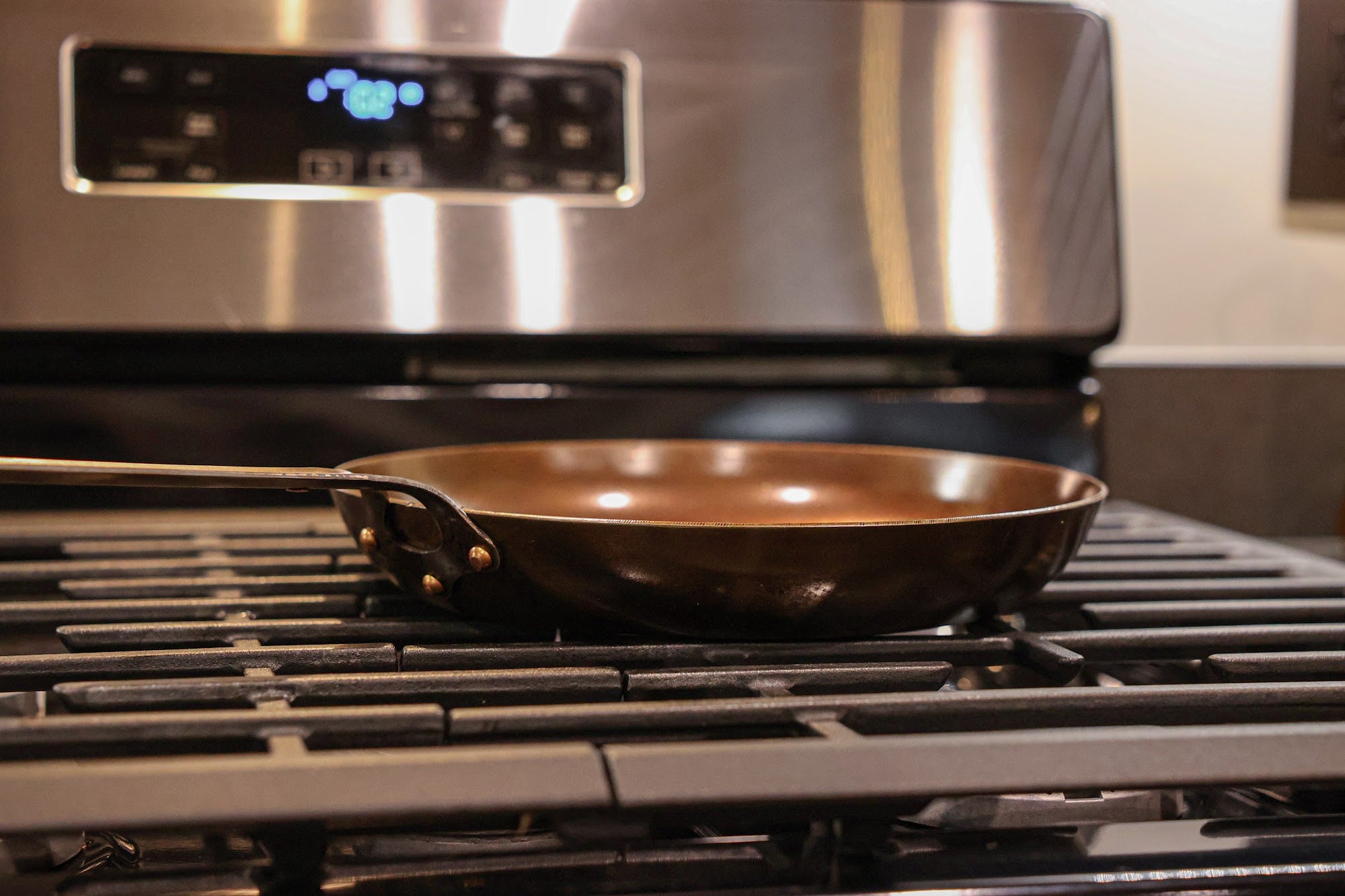 Side view of The Original carbon steel skillet on a gas range showing its tall walls and copper rivets